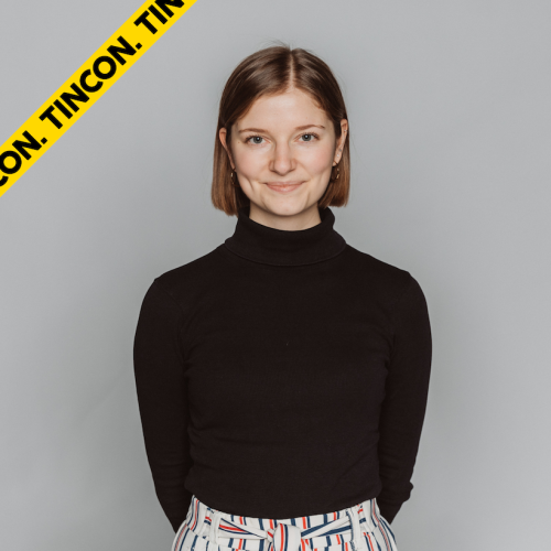 Auf dem Bild sieht man ein Portraitbild von Jule. Sie trägt einen schwarzen Rollkragenpullover und trägt ihre hellbraunen Haare als Bob. Sie lächelt in die Kamera.