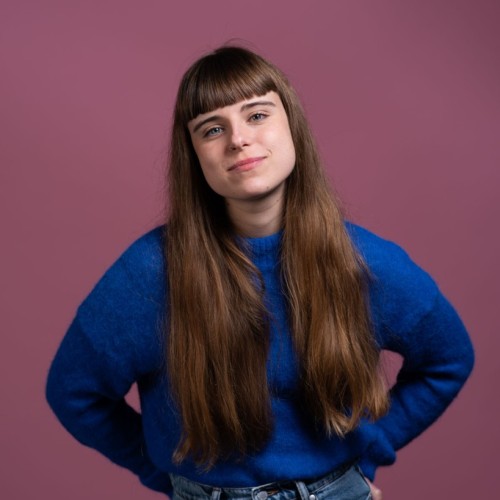 Frau mit langen braunen Haaren und Ponyfrisur, blauer Pullover